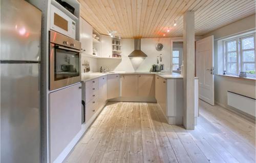 a kitchen with white cabinets and a wooden floor at Cozy Home In Hishult With Kitchen in Knäred