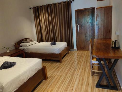 a room with two beds and a desk and a table at Amanda Boutique in Nongkhiaw