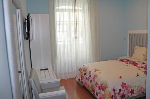 1 dormitorio con 1 cama, 1 silla y 1 ventana en Grande Oceano Guest House, en Oporto