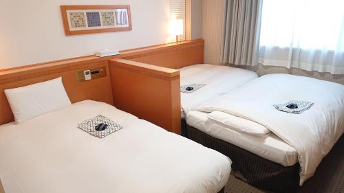 two twin beds in a hotel room at West Inn Fuji-Yoshida in Fujiyoshida