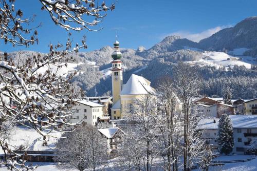 a church in the snow with mountains in the background at Steffi in Brixlegg