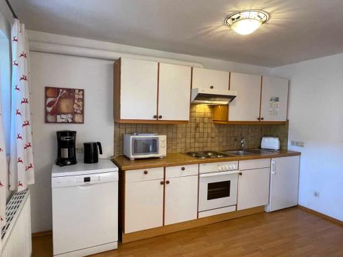 a kitchen with white cabinets and a microwave at Chalet Zauberflöte in Radstadt