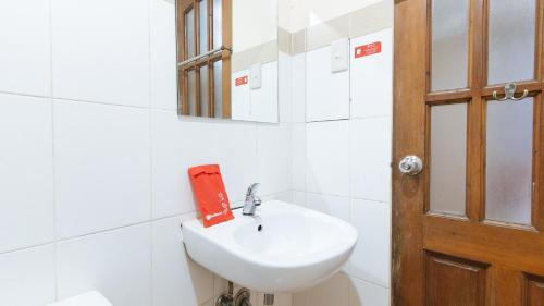 a white bathroom with a sink and a mirror at RedDoorz at DBuilders Rooms Ph2 Taguig in Manila