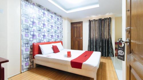 a bedroom with a bed with red pillows and a door at RedDoorz at DBuilders Rooms Ph2 Taguig in Manila