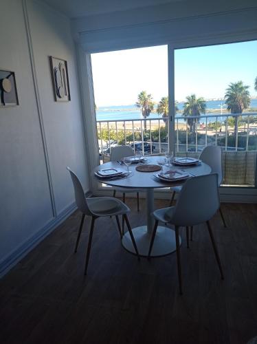 une salle à manger avec une table et des chaises et une grande fenêtre dans l'établissement Appartement vue mer, plage à 20m, à Gruissan