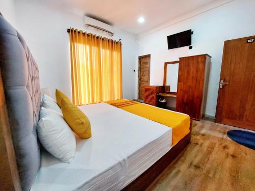 a bedroom with a large bed with a yellow curtain at Catch Up Dambulla in Dambulla