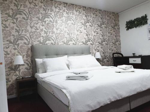 a bedroom with a large bed with white sheets at Swiss Plus Hotel in Bihać