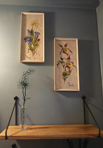 two pictures of flowers on a wall with a wooden shelf at Little Oakhurst in Clitheroe