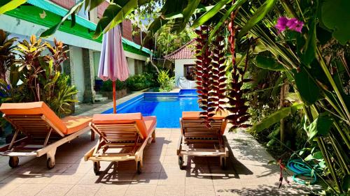 a group of chairs and an umbrella next to a pool at Ellenbrook Rooms 17 by Mulia Cottage in Seminyak