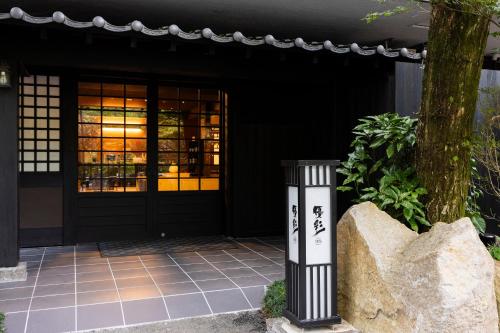 a building with a black door and a tree at Yusai Bekkan in Minamioguni