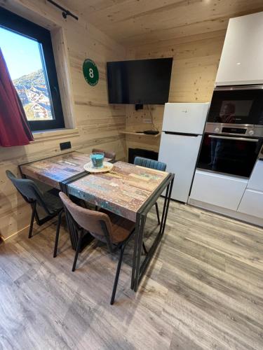 a kitchen with a table with chairs and a refrigerator at Les appartements de Makalu Val Thorens in Val Thorens