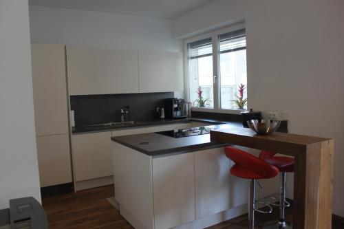 a kitchen with white cabinets and a counter with red stools at Penthouse Julia nähe Badesee mit Infrarotsauna -Zell am See Kaprun in Niedernsill