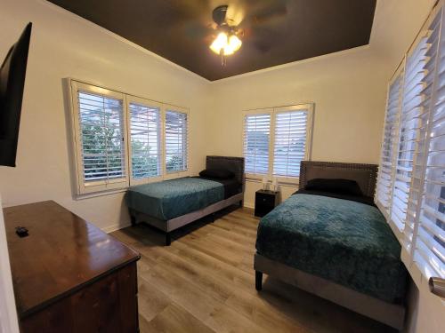 a bedroom with two beds and a table and windows at 3 bedroom top story apartment near Pico blvd in Los Angeles