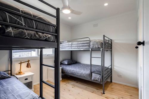 a bedroom with two bunk beds and a desk at Bellarine Retreat - Pet friendly in Portarlington