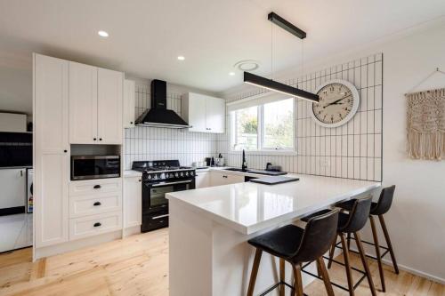 a kitchen with white cabinets and a clock on the wall at Bellarine Retreat - Pet friendly in Portarlington