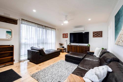 a living room with a leather couch and a flat screen tv at Bellarine Retreat - Pet friendly in Portarlington