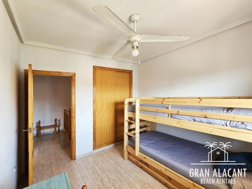Zimmer mit 2 Etagenbetten und einem Deckenventilator. in der Unterkunft Adosado familiar Novamar 33 in Santa Pola