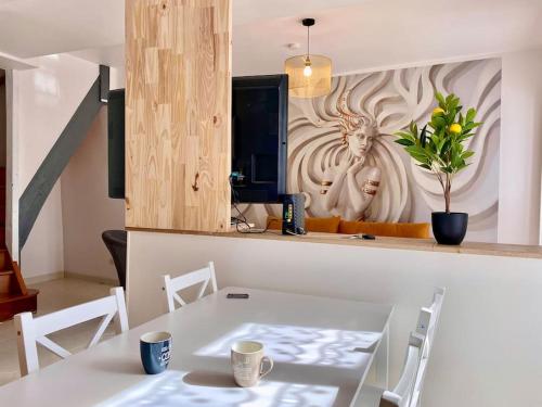 ein weißer Tisch und Stühle in einer Küche mit einer Wand in der Unterkunft Maison 2 chambres, village calme - Village Vaux 3 minutes Auxerre in Auxerre