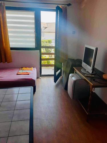 a small room with a bed and a computer on a desk at Vila Nina 