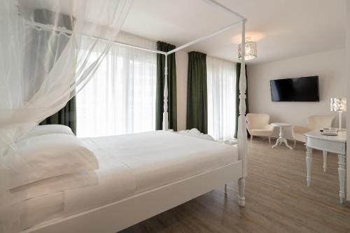 a white bedroom with a bed and a table and a television at Fantinello Hotel in Caorle