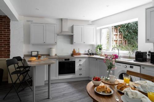 a kitchen with white cabinets and a table with food on it at Classy two bed home - close to town centre & beach in Exmouth