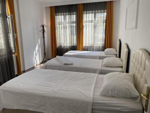 three beds in a hotel room with windows at Medi Otel in Samsun