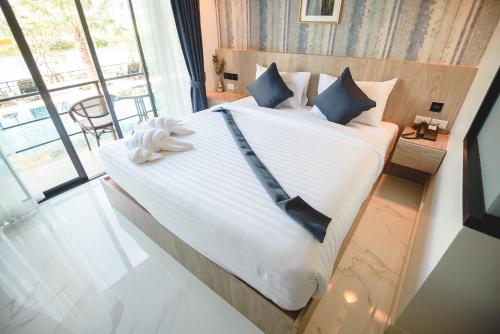 a bedroom with a large bed with a large window at Phuengluang Riverside Hotel Chanthaburi in Chanthaburi