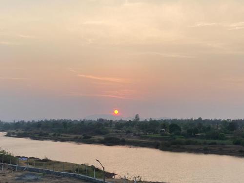 a sunset over a river with the sun in the sky at Krishna Villa in Shirwal
