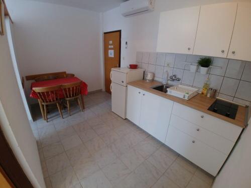 a kitchen with white cabinets and a table with a red table cloth at Apartment Svetka in Sali