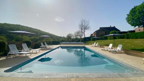 une piscine avec chaises et parasols dans l'établissement Chez Louise, à Vitrac