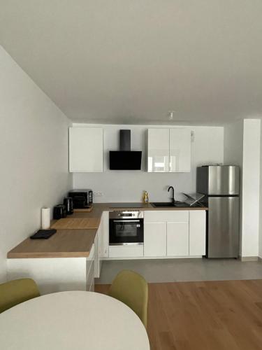 a kitchen with white cabinets and stainless steel appliances at Appartement cosy, proche transports Paris in Chevilly-Larue