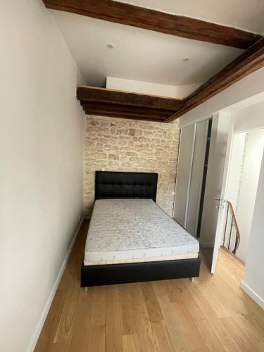 un lit dans une chambre avec un mur de briques dans l'établissement appartements sympas et confortables près de Paris, à Nanterre
