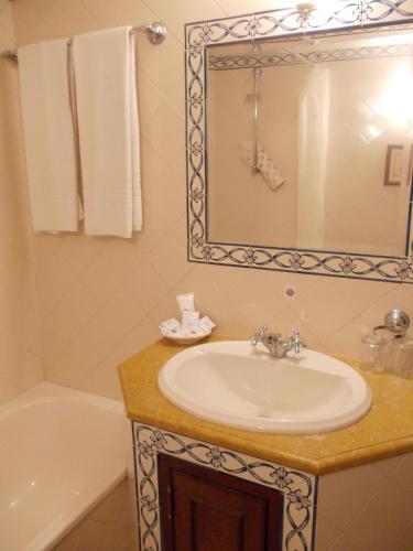 a bathroom with a sink and a mirror and a tub at Casa de S. Thiago do Castelo in Óbidos
