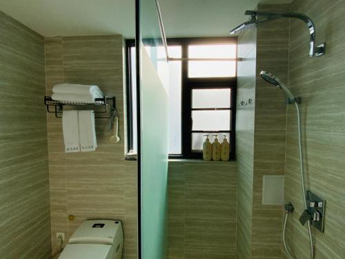 a bathroom with a shower and a toilet and a window at 叁三民宿 in Dali