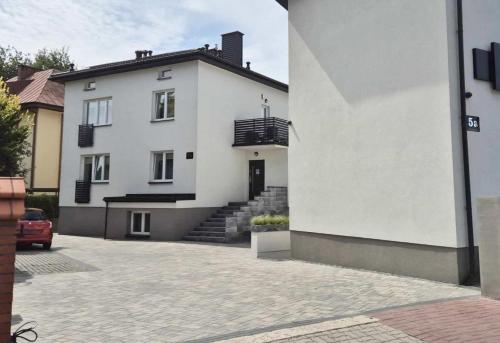 a white house with a staircase in front of it at H2U LUX Hostel Dla Ciebie in Mława