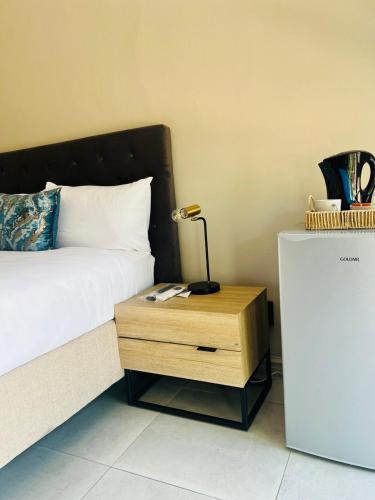 a bedroom with a bed and a night stand with a lamp at Purple Steps Guest House in Kimberley