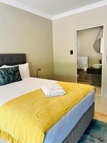 a bedroom with a bed with a yellow blanket on it at Purple Steps Guest House in Kimberley