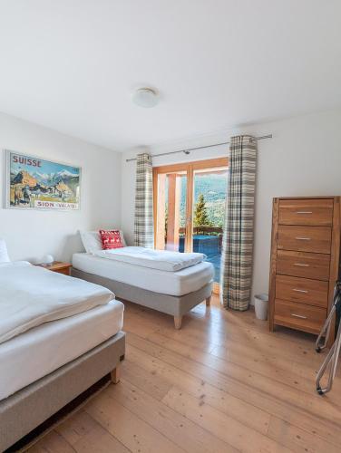 a bedroom with two beds and a window at Paisible apt cheminée, terrasse, jardin, vue époustouflante in Veysonnaz