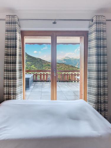 a bedroom with a bed and a large window at Paisible apt cheminée, terrasse, jardin, vue époustouflante in Veysonnaz