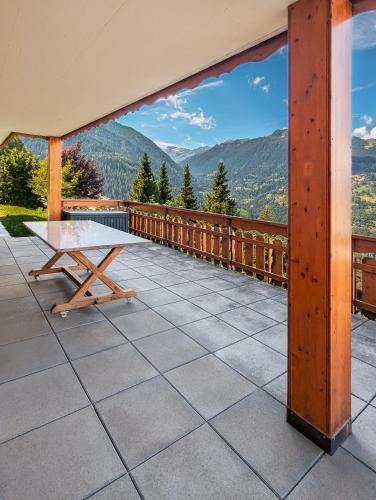 a table on a balcony with a view of mountains at Paisible apt cheminée, terrasse, jardin, vue époustouflante in Veysonnaz