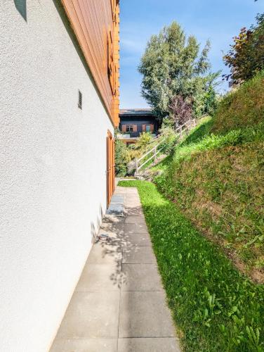 a sidewalk next to a building next to a hill at Paisible apt cheminée, terrasse, jardin, vue époustouflante in Veysonnaz