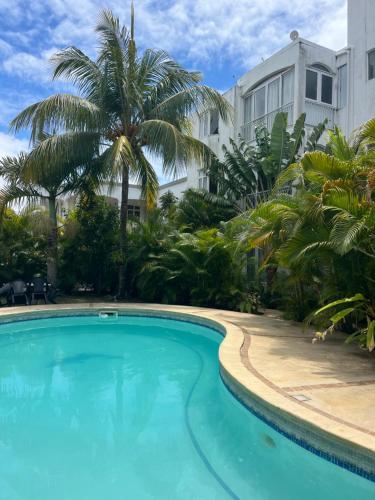 a swimming pool in front of a building with palm trees at Paradise Palms in Grand Baie