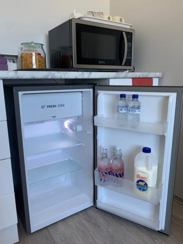 an open refrigerator with bottles of water and a microwave at Caversham B&B in Perth