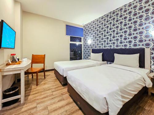 a hotel room with two beds and a table and a desk at Hotel 88 Kedungsari - Kedungdoro By WH in Surabaya