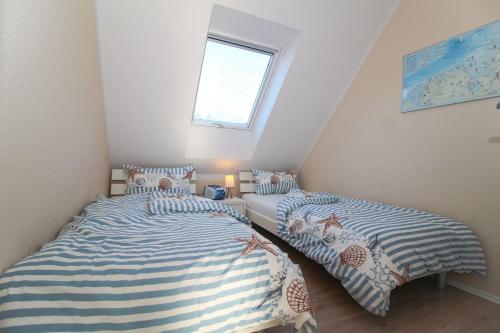 two twin beds in a bedroom with a window at FriesenZeit in Norden