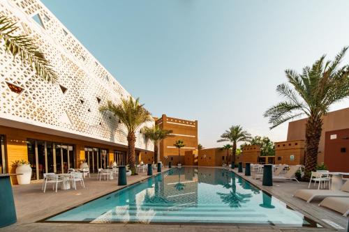 a pool in the middle of a building with palm trees at Vivienda Hotel and Villas, Diplomatic Quarter in Riyadh