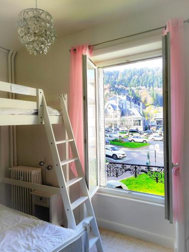 une chambre avec un lit superposé et une grande fenêtre dans l'établissement Le Beau Site appartement chaleureux et lumineux tout a pieds, à Mont-Dore