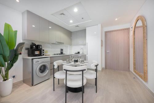 a kitchen with a table and a washing machine at Free housekeeping visits during your stay - StayShort - Modern 1-Bedroom Apartment at Azizi Riviera in Meydan in Dubai