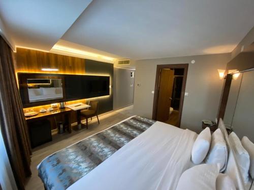 a bedroom with a large white bed and a desk at Yucel Hotel in Usak