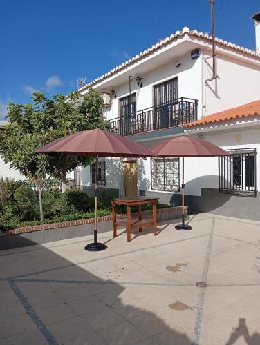 a picnic table and two umbrellas in front of a building at Villa Turística Miguel in Pulianas